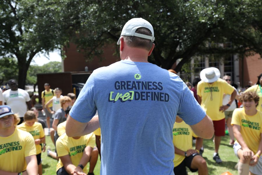 Dr. John White speaks to Faith & Sports Institute summer campers. T-shirt says Greatness Redefined.