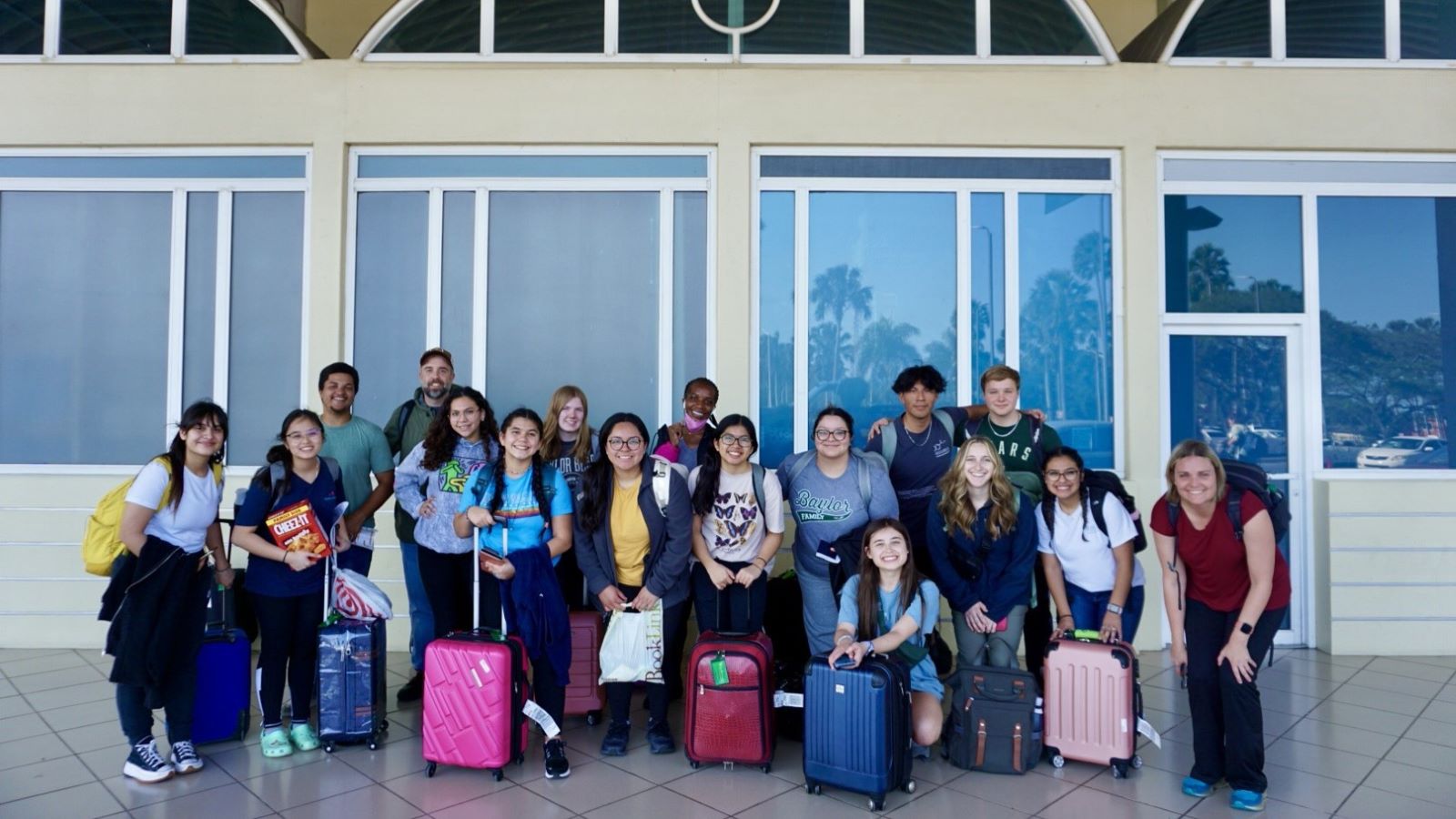 Group of students with luggage outside of an airport