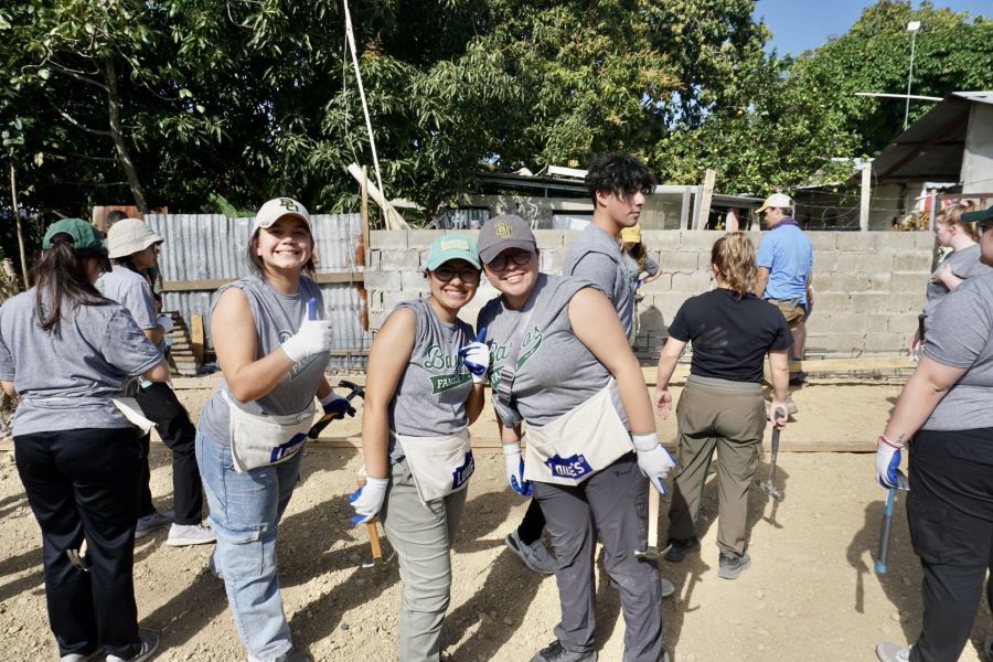 Three Baylor students in t-shirts and toolbelts working on building a house in the Dominican Republic