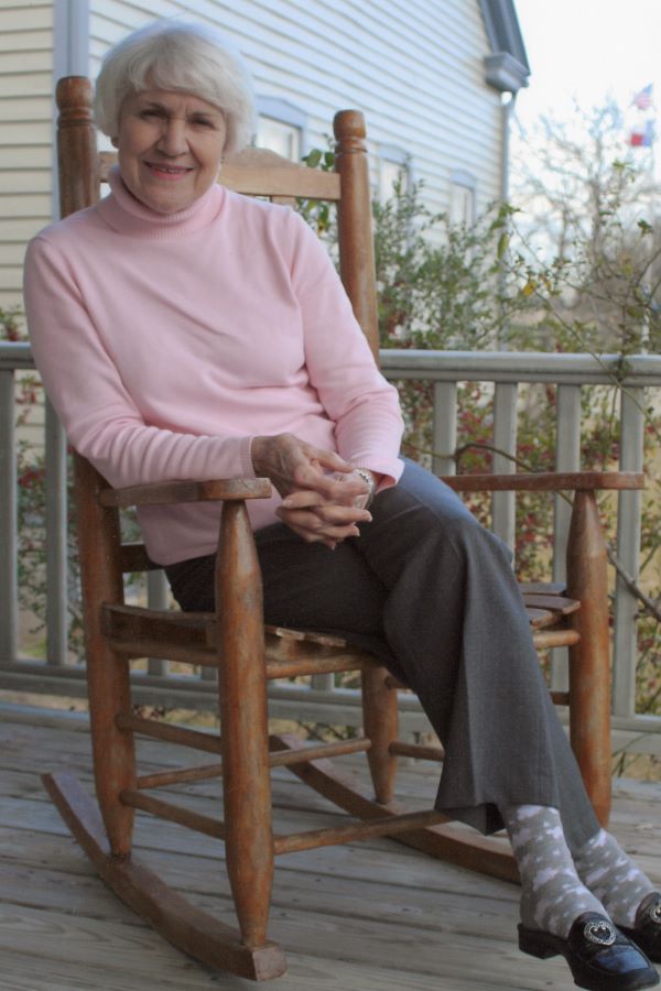 Lanella Spinks Gray with a pink sweater sitting in a rocking chair