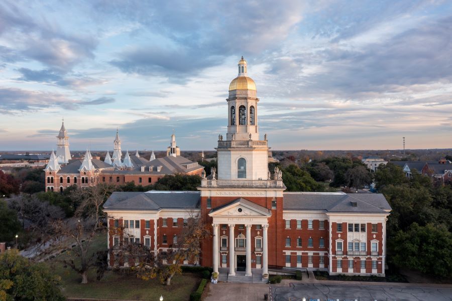 Dusk over Baylor's Pat Neff Hall with a gold bell tower and spires of Old Main.