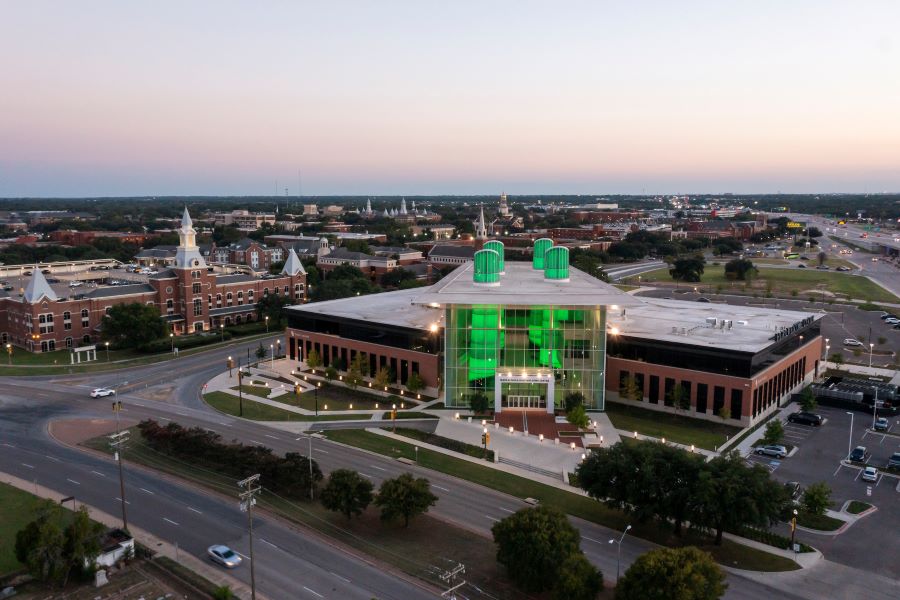 Baylor's Mark and Paula Hurd Welcome Center with its four columns lit in green.