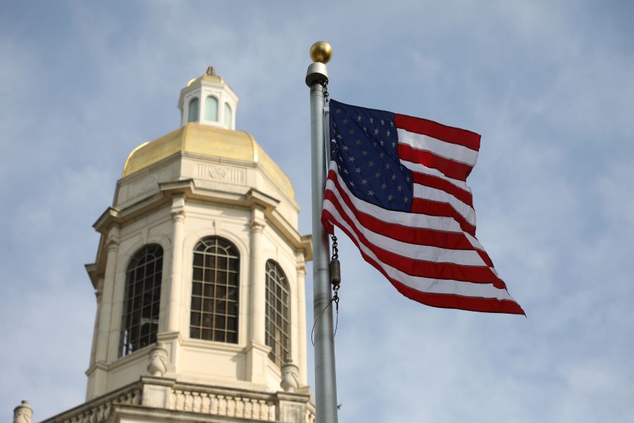 Gold bell tower of Baylor University's Pat Neff Hall with a red, white and blue American flag