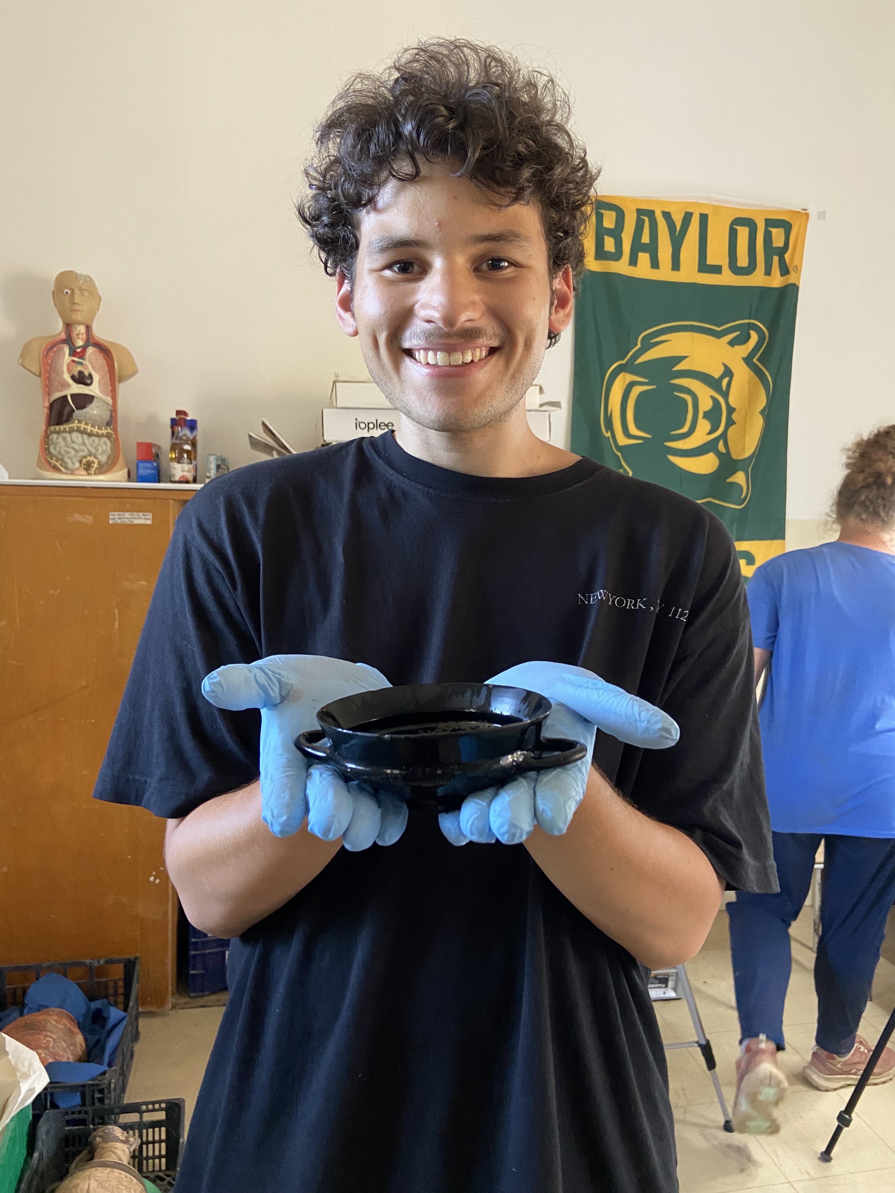 Student holding piece of pottery found in 7th century BC Etruscan tomb