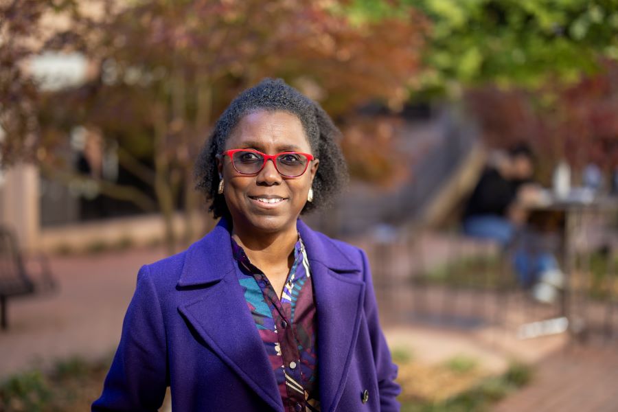Woman in purple jacket with red rimmed glasses