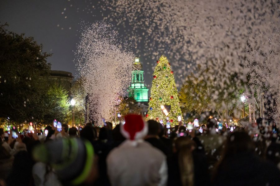Lighted Christmas tree with snow blowing around bystanders on the Baylor campus