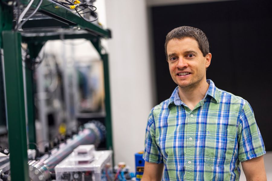 Baylor mechanical engineering professor Clayton Mulvihill in a green and blue checkered shirt in his engineering lab.