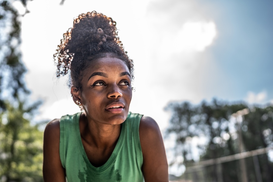 Young woman in green top sweating in the summer heat