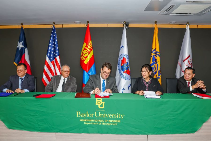 Five people with flags behind them sign an agreement on international initiative to strengthen judicial virtue, ethical leadership and professional responsibility within Mongolia's legal system
