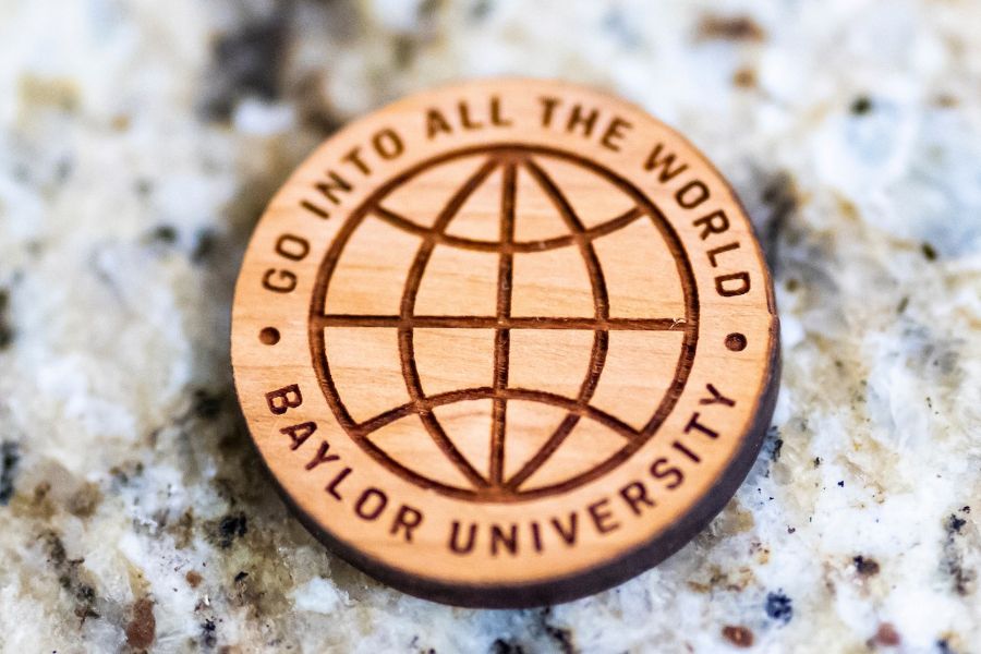 Wooden coin that shows a globe encircled by the words "Go Into All The World" Baylor University