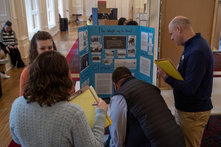 History fair judges ask questions as they study a student's history project