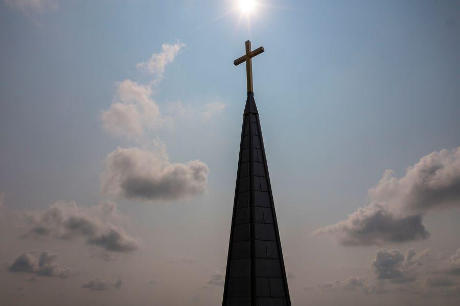 Steeple of Baylor's Truett Seminary beneath the sun with blue skies and clouds