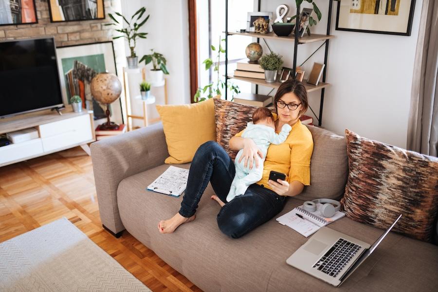mom holding baby while looking at smart phone