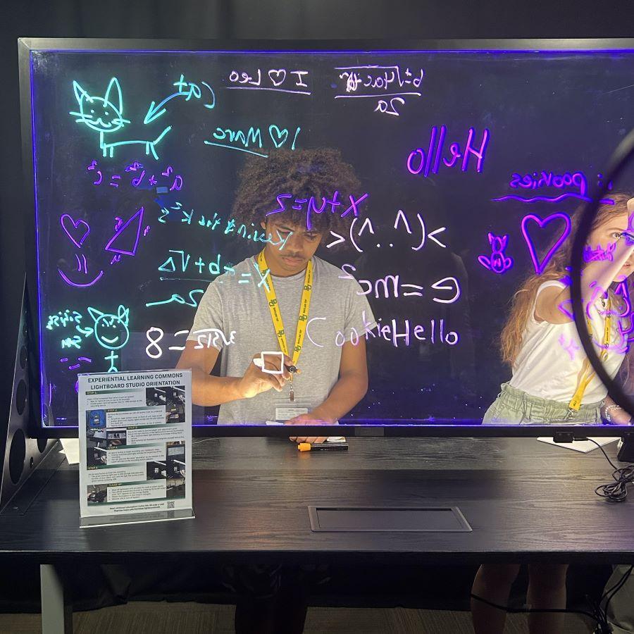 High school students writes on a light board