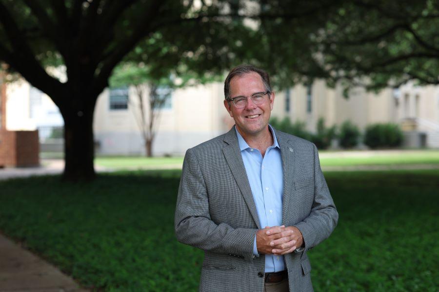 Dr. Charley Ramsey, University Chaplain and Dean of Spiritual Life at Baylor University, stands with a live oak tree and Waco Hall in the background