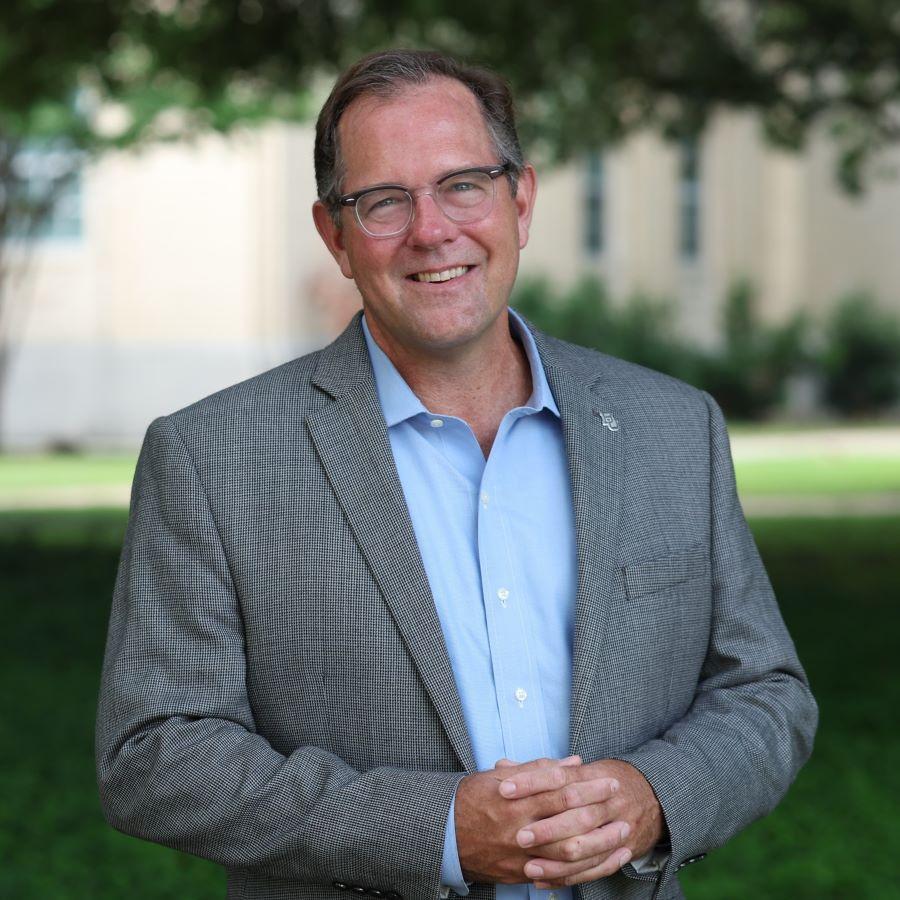 Dr. Charley Ramsey, University Chaplain and Dean of Spiritual Life at Baylor University, stands with a live oak tree and Waco Hall in the background