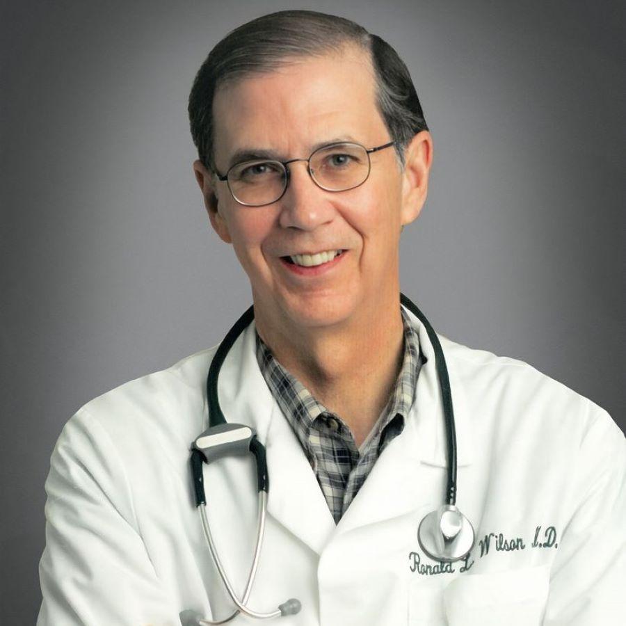 Dr. Ronald L. Wilson wearing a white lab coat and stethoscope.