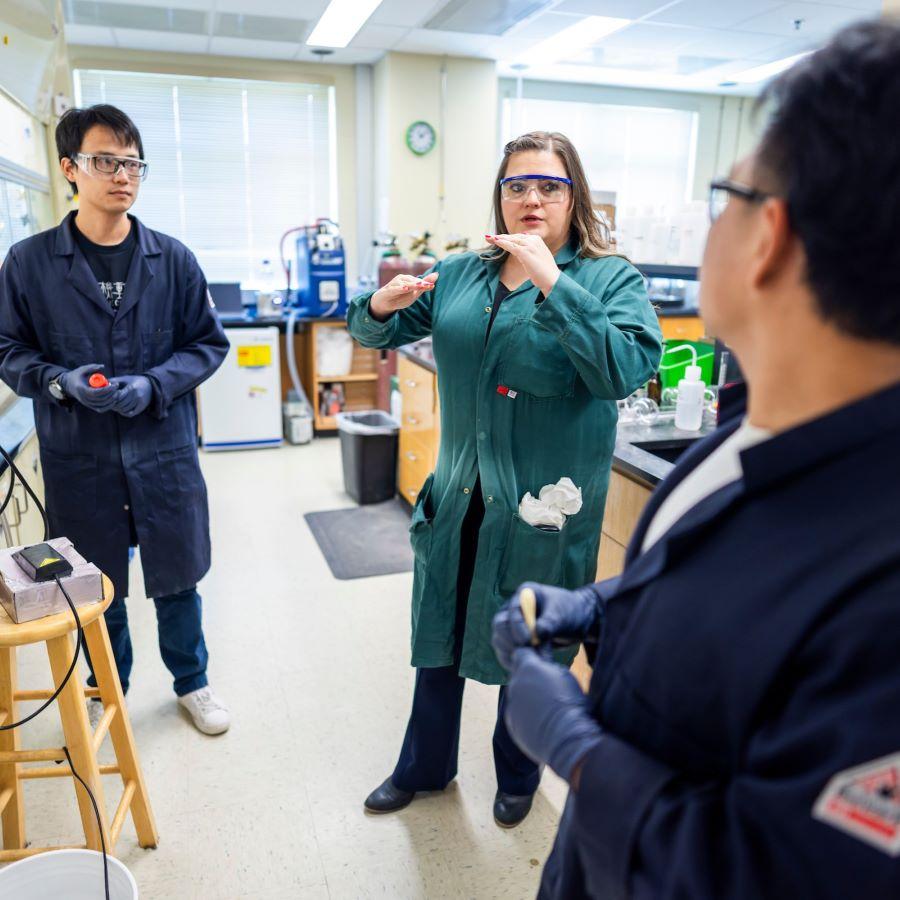 Baylor University chemistry professor Liela Romero in a green lab coat in her chemistry lab with graduates students
