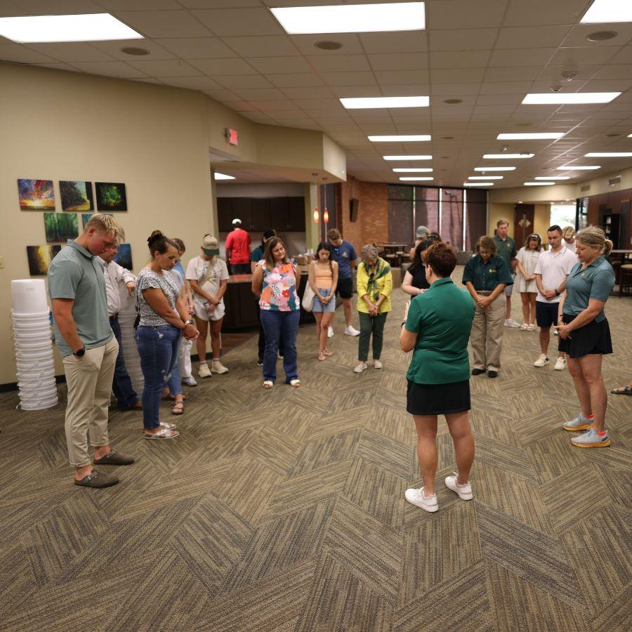 Baylor Associate Chaplain Rebecca Kennedy leads prayer before students, faculty and staff pick up supplies on tables to pack into disaster relief kits.