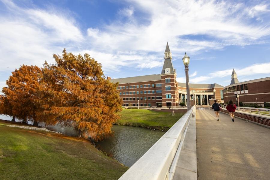 Photo of Baylor University in the fall with students walking over a bridge
