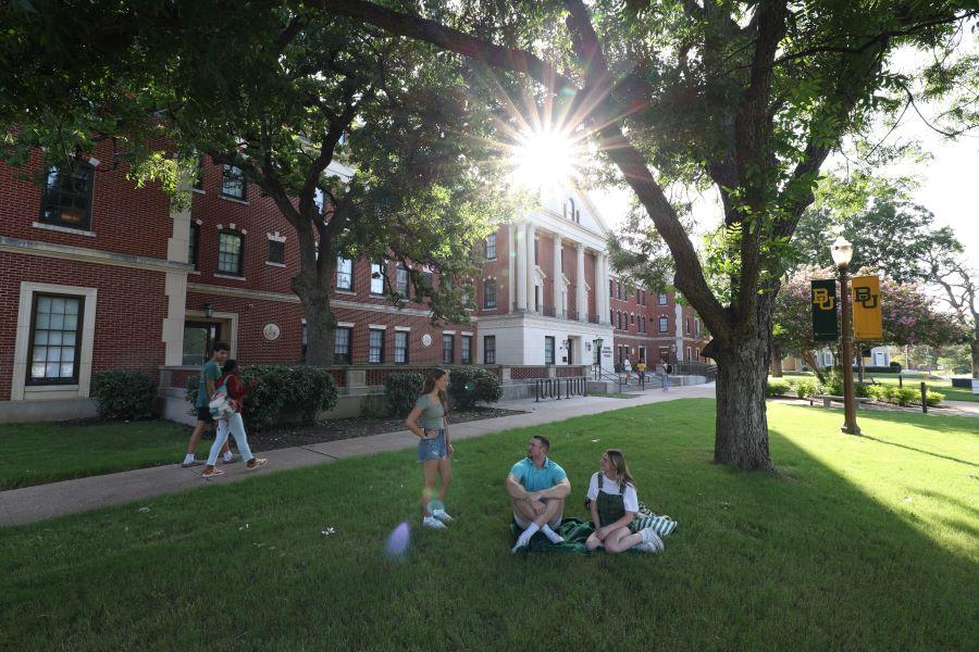 Student walking on the sidewalk and on the grounds of the Honors Residential College at Baylor University