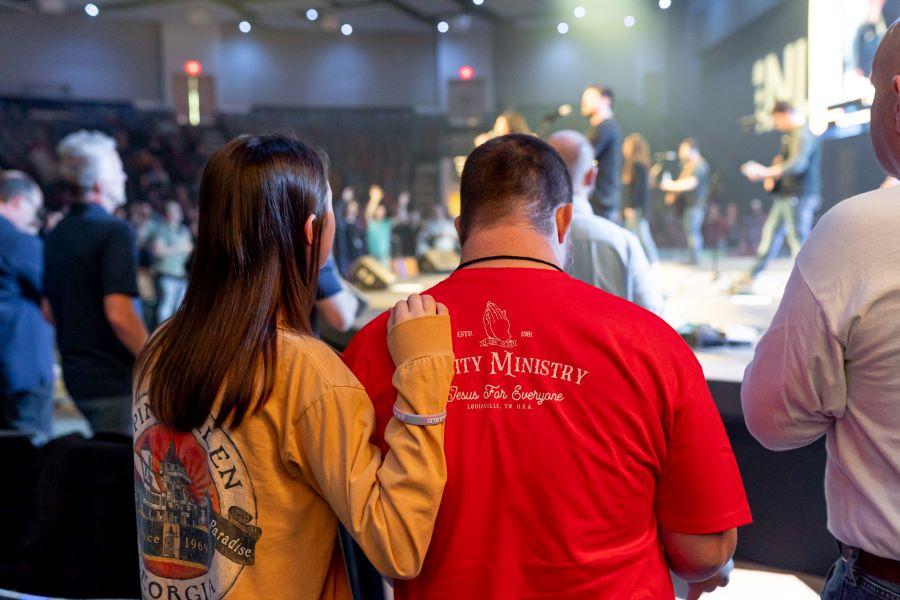 Woman with arm on man's shoulder facing toward church stage