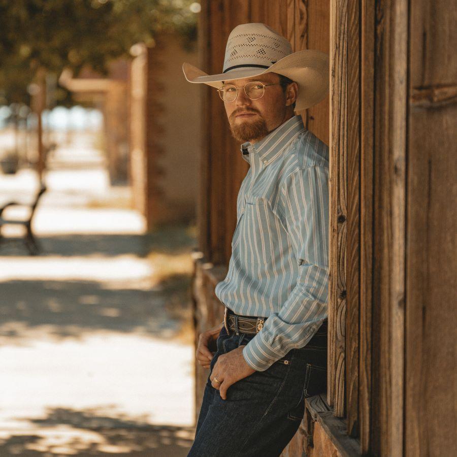 Country singer Tyce Delk in a cowboy hat, striped shirt and blue jeans