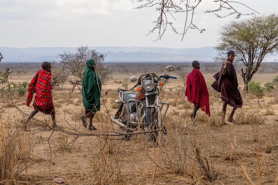 Hazda hunters walk past motorcycle 