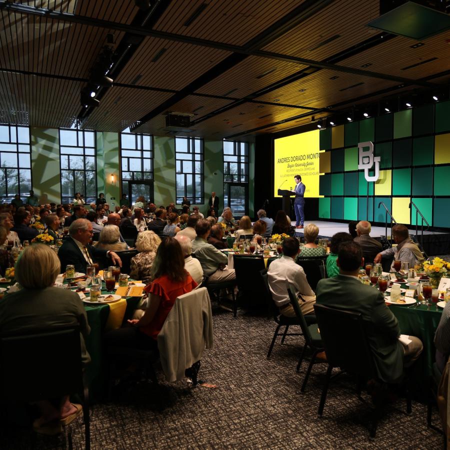 A college student and scholarship recipient speaks from a stage in front of guests at a scholarship banquet.