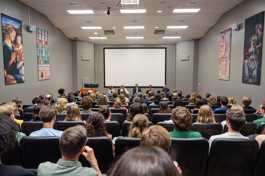 A full lecture hall of people listening to a panel discussion about theatre and playwriting.