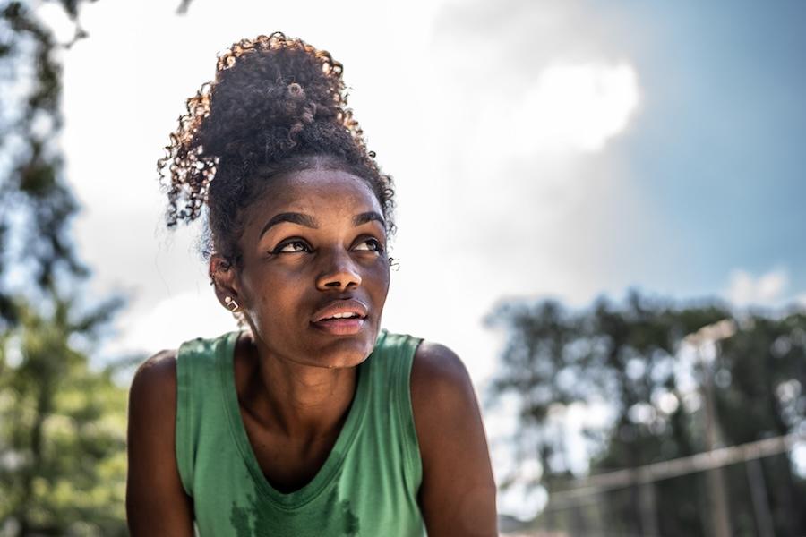 Young woman in green top sweating in the summer heat