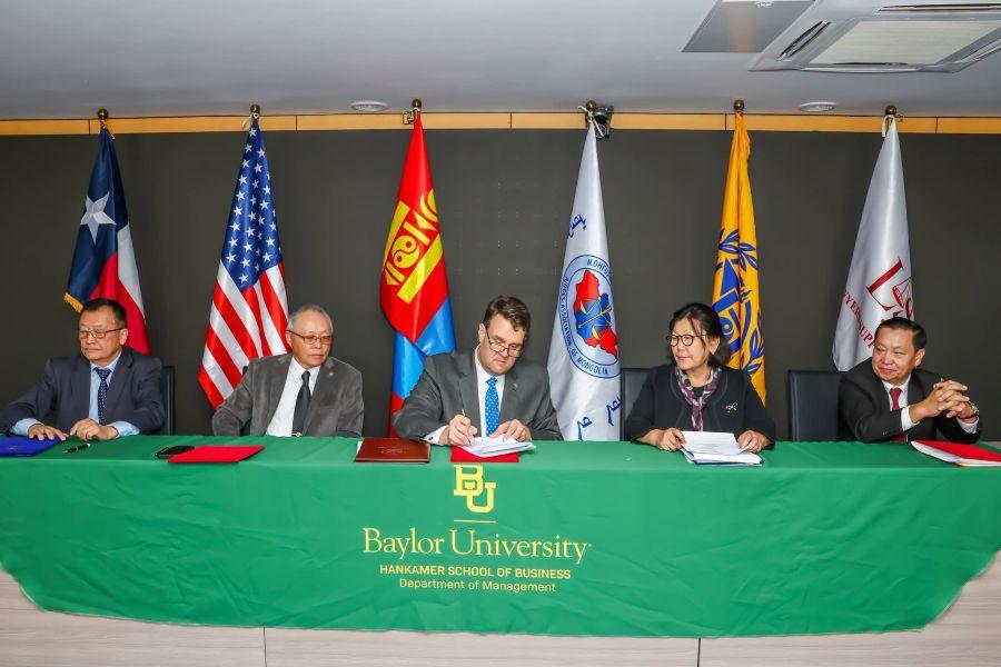 Five people with flags behind them sign an agreement on international initiative to strengthen judicial virtue, ethical leadership and professional responsibility within Mongolia's legal system