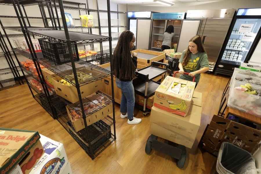 Staff members stocking a store with fresh fruits and vegetables and other items.